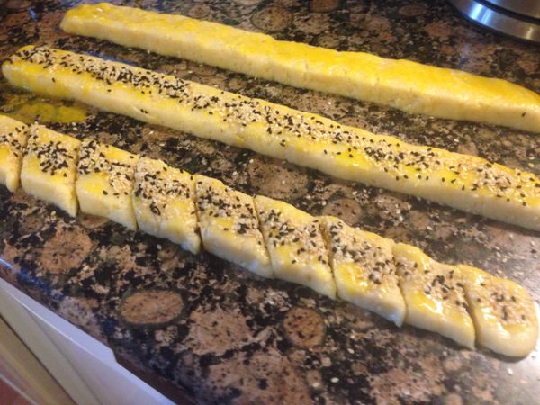 把麵團用手捏長，三條都一樣，捏長以後用菜刀把長的兩邊整型整齊，塗上蛋黃以後，灑上黑白混和的芝麻如圖，再切成一樣大小的菱形如圖，再用菜刀鏟起來放在有烤盤紙的烤盤上，依序擺好