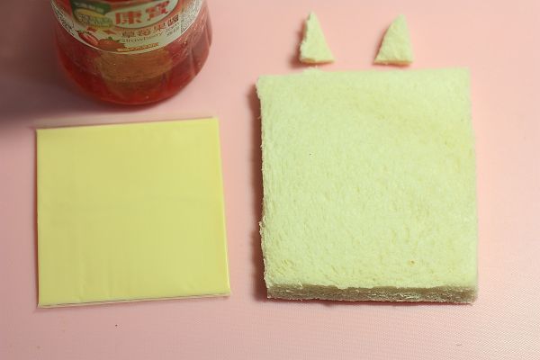 拿出二片全家-元氣土司去邊，每片土司的其中一面抹上適量草莓果醬，並放上一片起司片捲起來，放入野餐盒中央，接著放入適量的生菜沙拉在土司捲上下方。接著將剪好的貓咪耳朵抹點草莓果醬，黏在土司捲適當位置上。海苔，剪出眼睛、鼻子和貓咪鬍鬚，用草莓果醬黏在土司捲上。再放上貓掌即可。