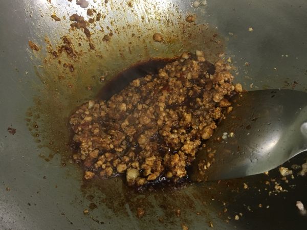 適量的油先炒香蒜末，再放入絞肉炒至變白，然後放入3大匙辣豆瓣醬續炒，再放3大匙醬油炒香