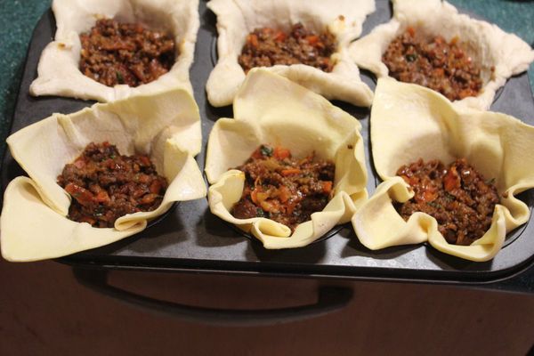 將酥皮在室溫放軟後，壓入瑪芬烤模。將餡料填入。