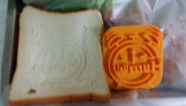 元氣土司用麵包膜壓出鬧鐘突圖案【餓～】，沾雞蛋液。