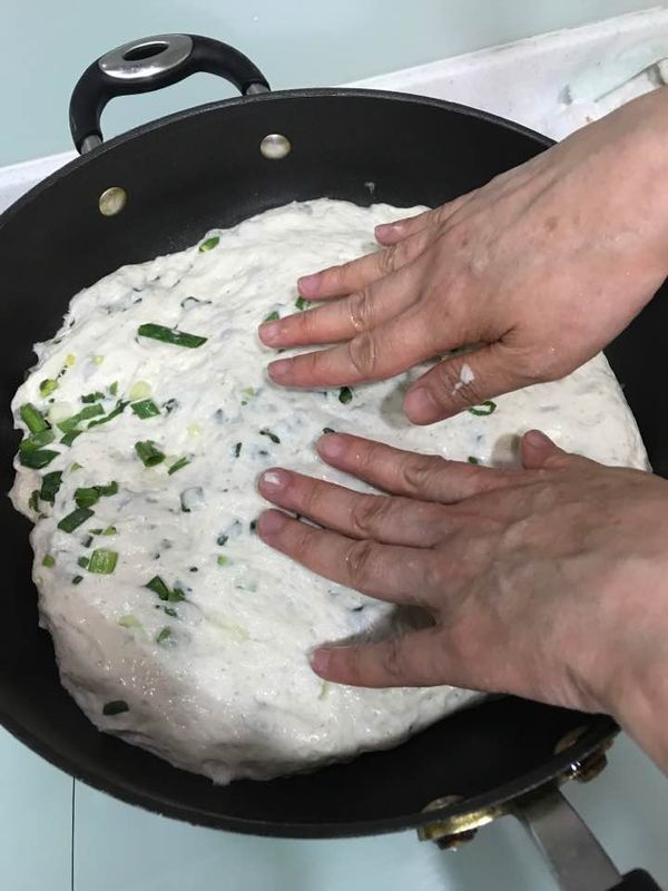 大一點的不沾鍋用紙巾抺上少許油,將麵團放入,手抺少許油將麵團攤平均在鍋裡,蓋上鍋蓋,小火慢烘約8分鐘.搖一下鍋有滑動並有脆皮的聲音,用鏟往上翻一點點低頭看一下是不是已烘至自己要的金黃色.若滿意,翻面.