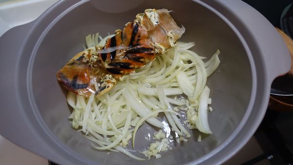 拿出ㄧ只鍋，冷鍋時放入適量的橄欖油/蒜末/龍蝦殼拌炒至蒜香味出來，接著再放入洋蔥絲炒至變軟。