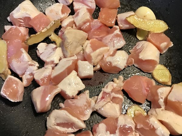 倒一湯匙麻油以小火炒香薑片、大蒜，稍微煸至微焦再加入雞丁。