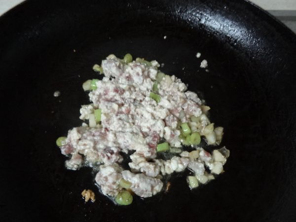 原鍋剩餘的油爆香蔥白、蒜末，再放入絞碎的豆腐和絞肉拌炒，半熟後加入糖、醬油及半杯水，拌炒至熟熱，最後加入蔥青後起鍋。