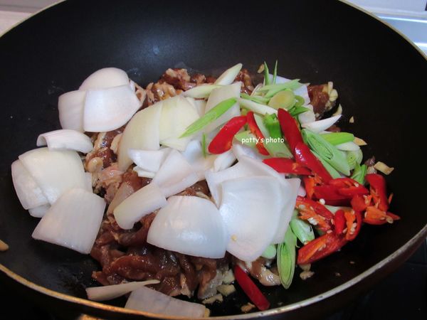 放入洋蔥片、青蒜和辣椒，繼續拌炒出香氣。