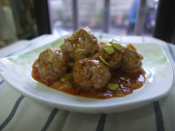 起鍋下蕃茄醬、香油、糖小火慢炒到糖溶解，下義大利香料攪拌，加水、白醋、黑醋、醬油拌勻煮滾熄火，加洋葱丁再開火加熱。
將肉丸子加入茄汁中煮到收汁，放入毛豆仁、香油後即可盛盤。