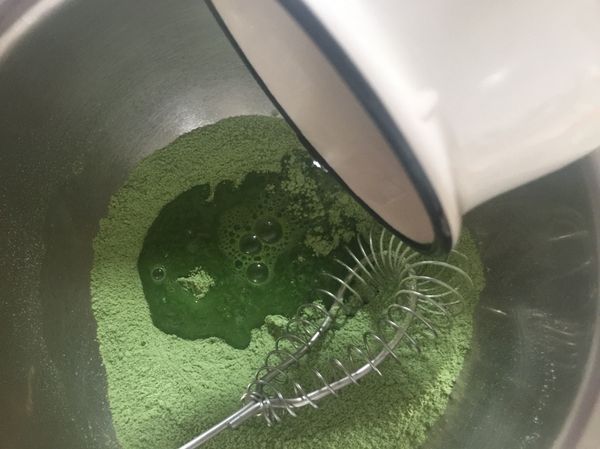 鋼盆裡放入糖、過篩的麵粉、抹茶粉倒入溫開水拌勻